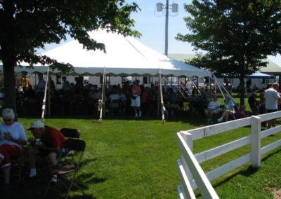 People eating under a large party tent